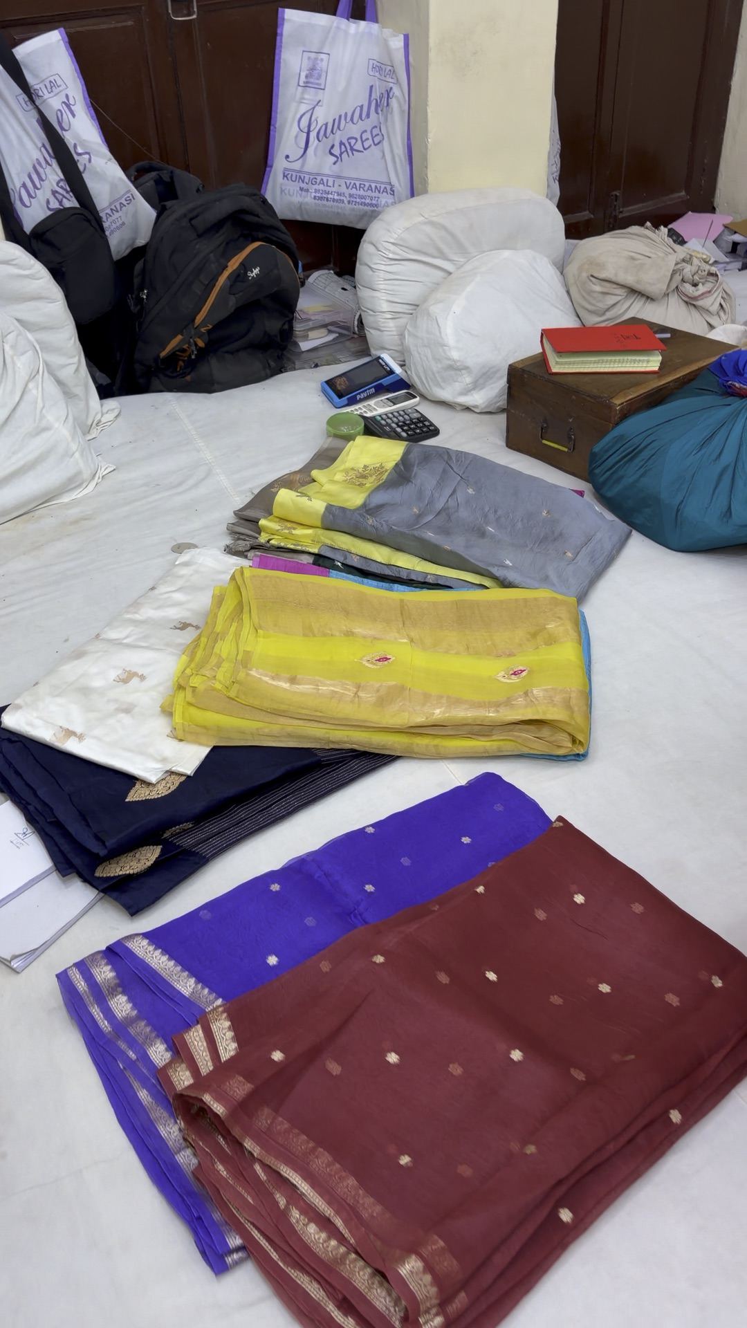 Banarasi sarees opened out on the white gaddi floor